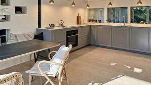 A modern kitchen with grey cabinets, a central island, and pendant lighting.