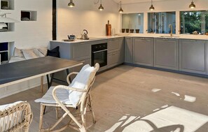 A modern kitchen with grey cabinets, a central island, and pendant lighting.