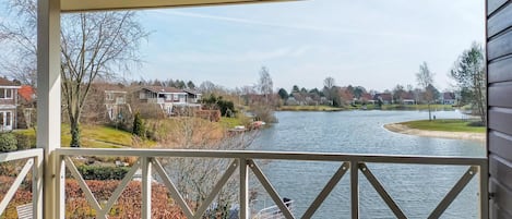 A view from a covered balcony overlooking a river, with houses and trees in the background.