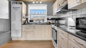 Uma cozinha moderna com forno embutido, geladeira de aço inoxidável e uma grande janela com vista para a paisagem urbana.