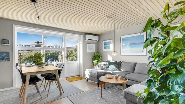 Uma sala de estar moderna com área de jantar, janelas amplas e vista para o exterior.