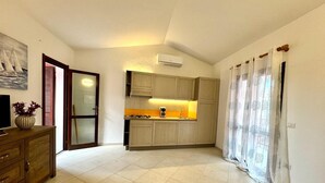 Een kleine woonruimte met een kitchenette, een eethoek en een bank.