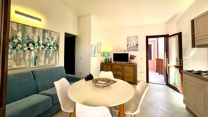 Een moderne woonkamer met een bank, eettafel, stoelen, een televisie en kunstwerken aan de muur.