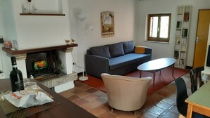 Un soggiorno con camino, un divano, un tavolo e una libreria.