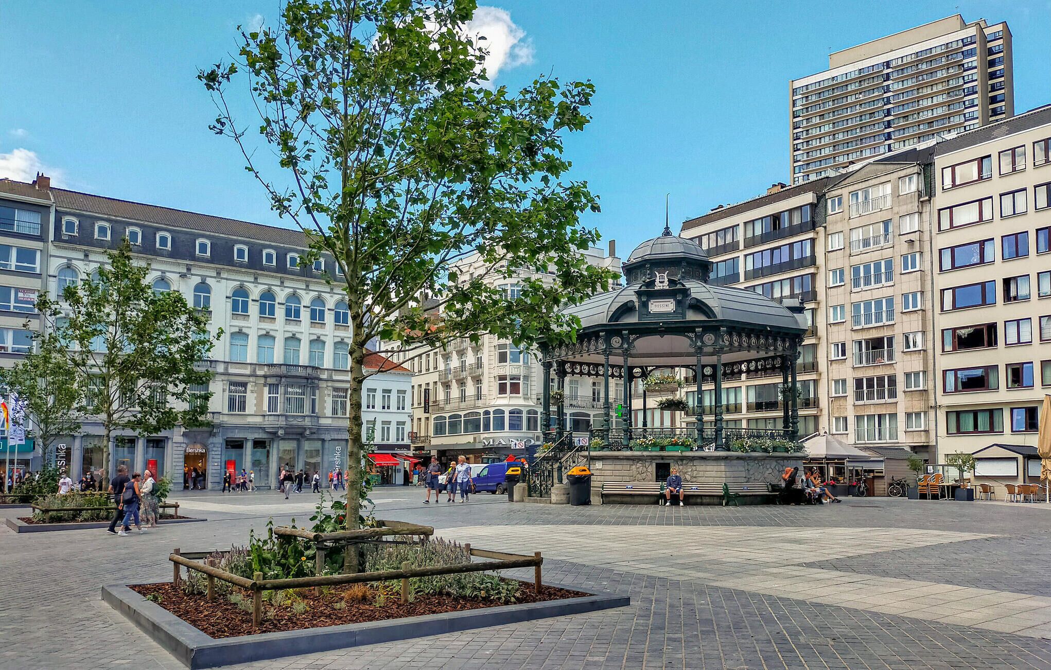 A public square with a central gazebo, surrounded by multi-story buildings, some with visible signage.