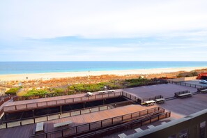 A rooftop terrace with a view of the beach and ocean.
