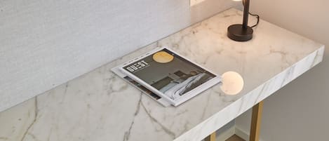 A modern workspace with a marble countertop, a blue chair, and a desk lamp.