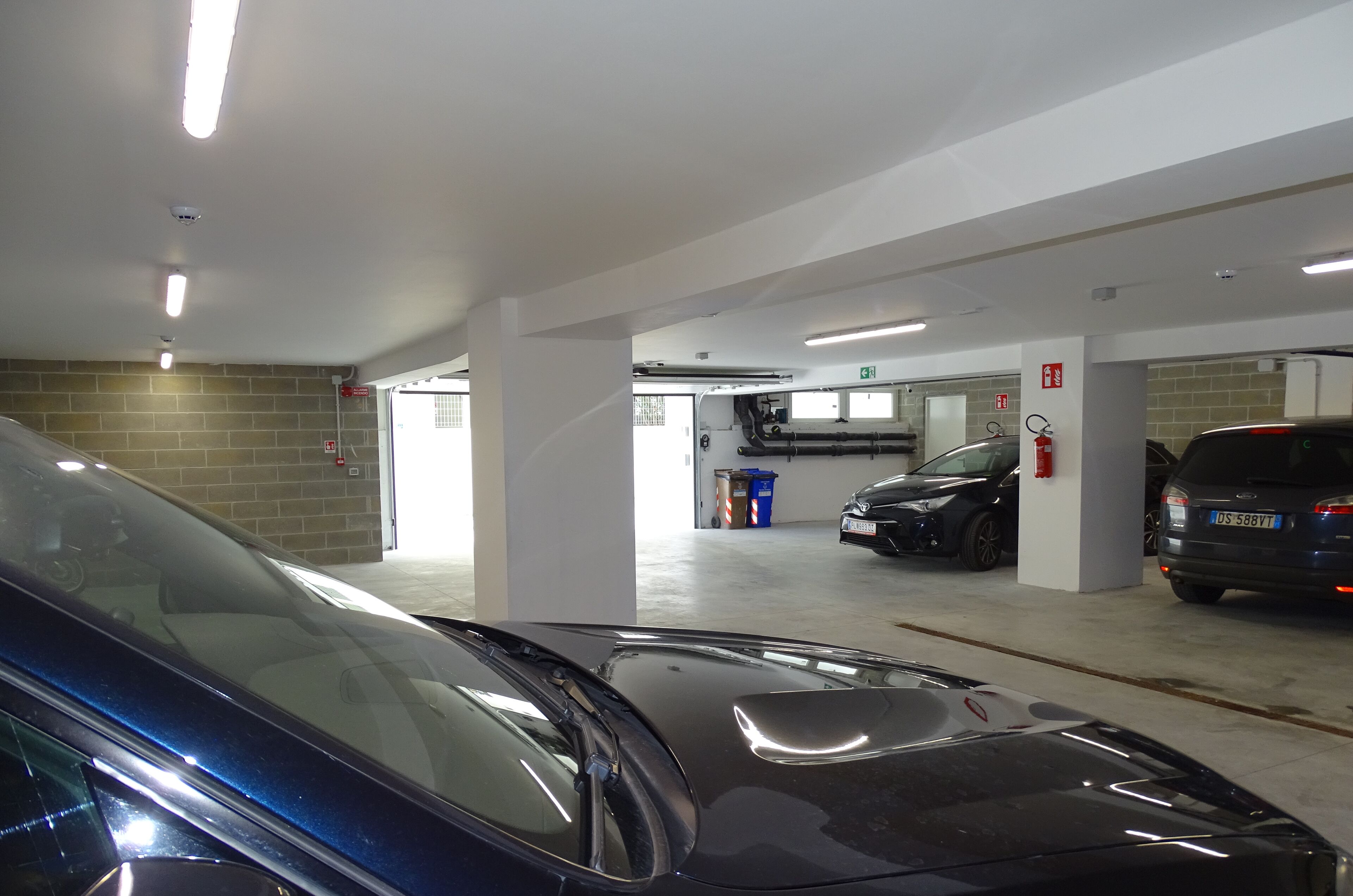 A parking garage with multiple levels, cars parked, and emergency equipment visible.