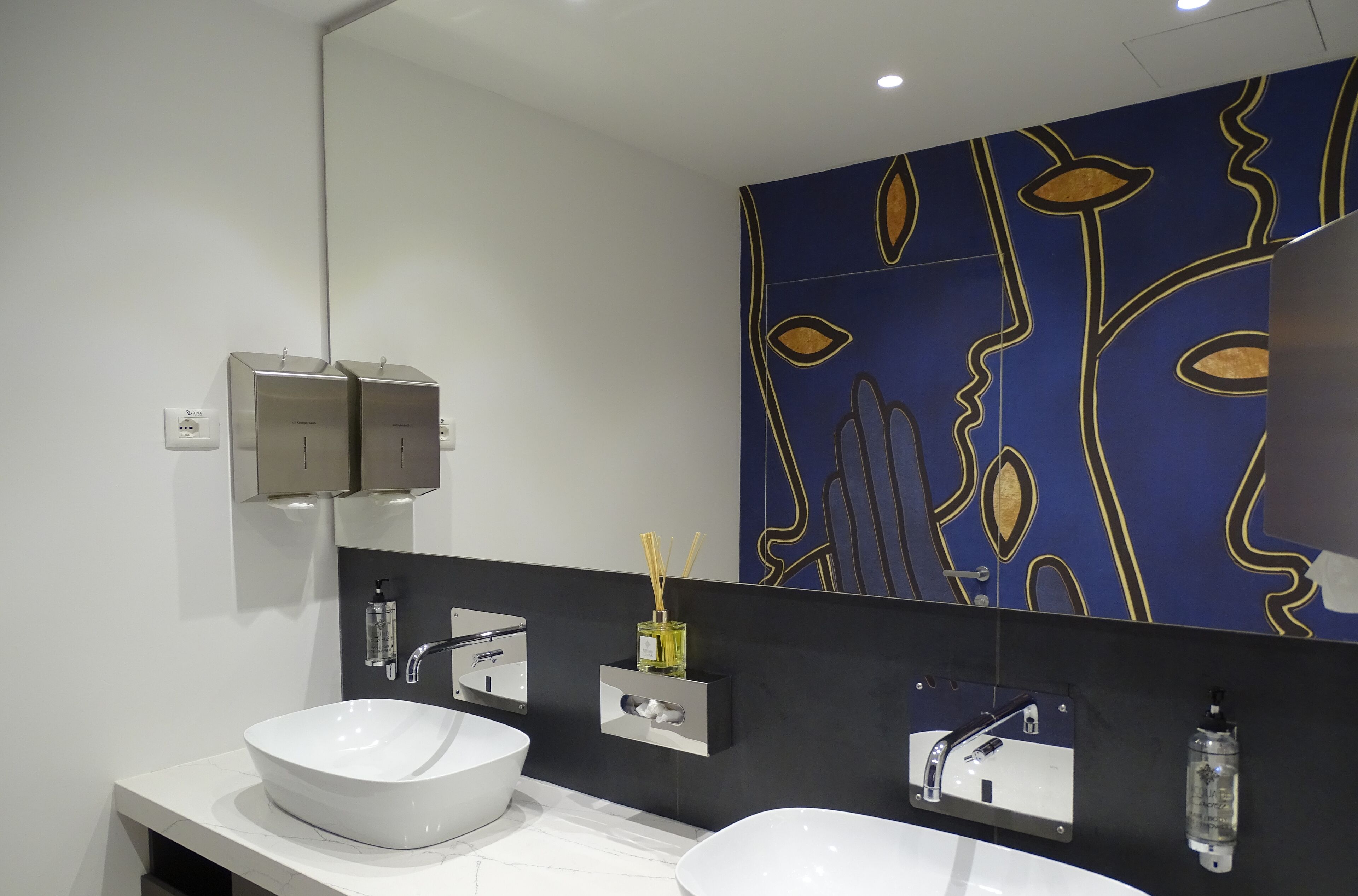 A modern bathroom with a large mirror, two sinks, and a decorative wall panel.