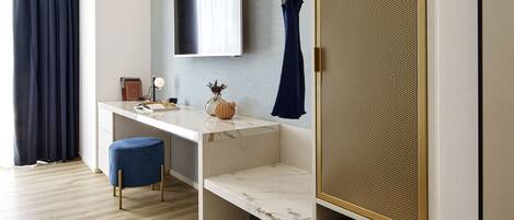 A modern room with a white desk, a mounted TV, a blue chair, and a decorative wall panel.