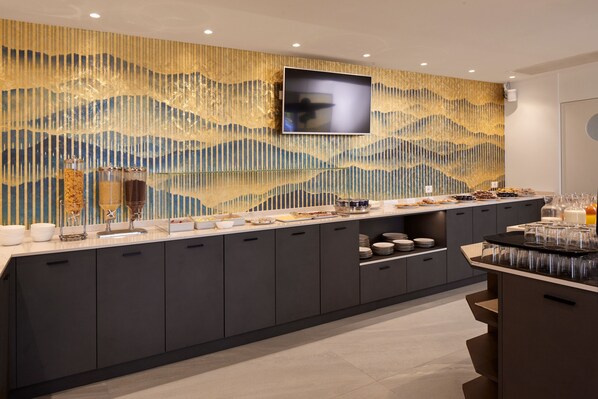 Una cocina moderna con una encimera amplia, armarios integrados y una pared decorativa con un televisor montado en la parte superior.