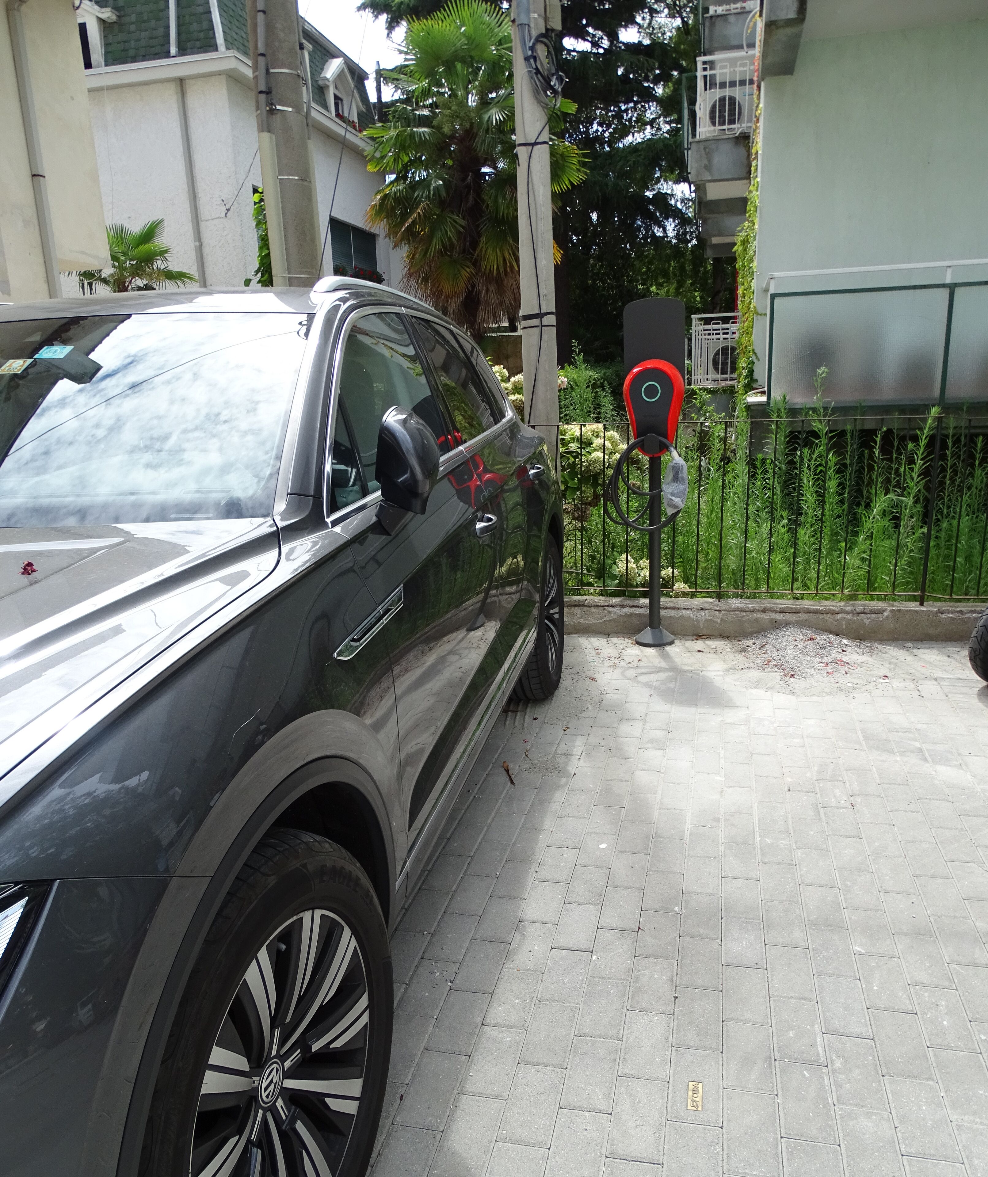 A parked car in a paved area with a charging station nearby.