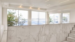Un interior moderno con paredes de mármol y ventanas amplias que dan a una masa de agua.