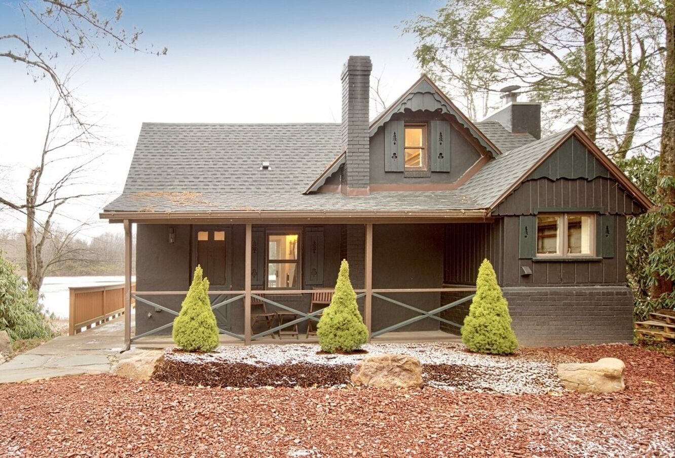 A house with a porch, a chimney, and three conical trees in the front yard.