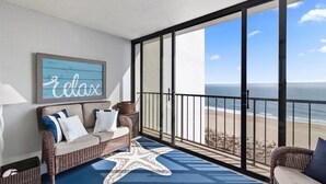 Un balcone con divano in vimini, tappeto a forma di stella marina e un cartello con la scritta 'relax'.
