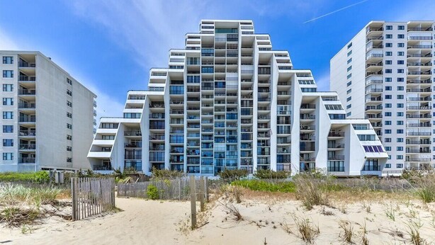 Un moderno hotel sulla spiaggia con diversi edifici a grattacielo, dotato di balconi e ampie finestre.
