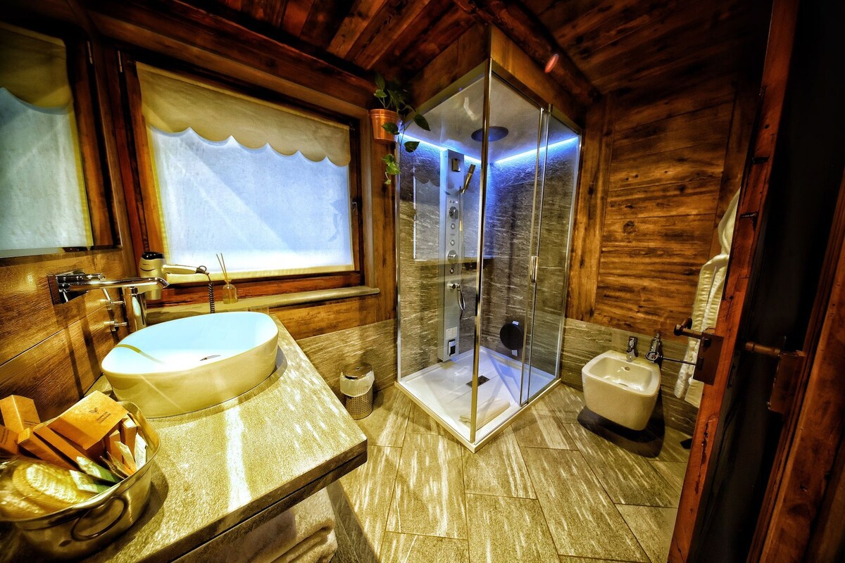 A wooden cabin bathroom with a large sink, a glass-enclosed shower, and a toilet.