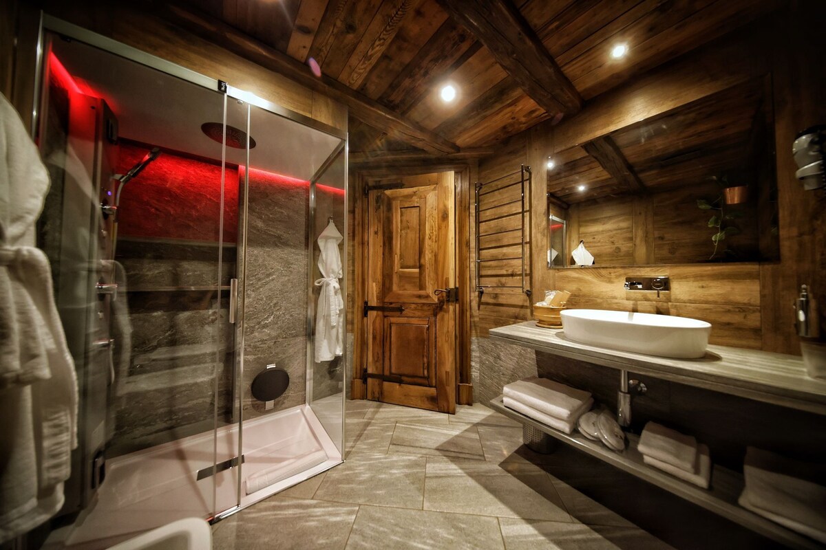 A modern bathroom with a glass-enclosed shower, wooden walls, a large sink, and a towel rack.