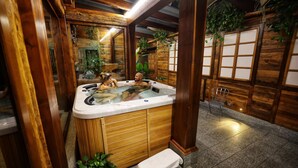 Ein Whirlpool in einem holzverkleideten Raum mit einer Bank und einem Sessel.