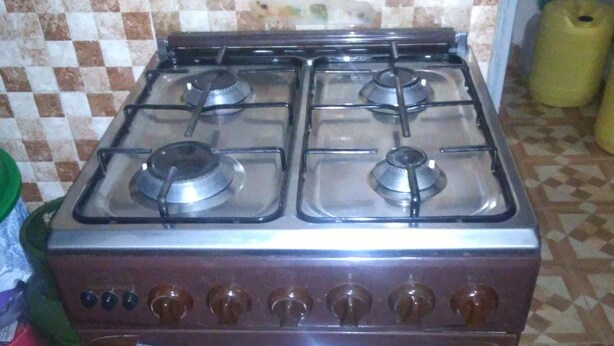 A kitchen with a gas stove and oven, checkered tile backsplash, and a tiled floor. - VIV HAVEN (Nairobi)