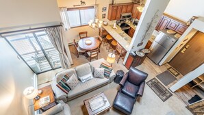 A spacious living area with a sofa, armchair, and coffee table, a dining area with a table and chairs, and a kitchen with wooden cabinets and appliances. - West Keystone Condo w/ Quiet Location and Wrap Around Porch, Mins to Shuttle! (Keystone)