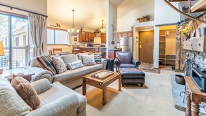 A spacious living room with a sofa, coffee table, and a fireplace. - West Keystone Condo w/ Quiet Location and Wrap Around Porch, Mins to Shuttle! (Keystone)