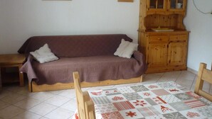 A living room with a brown sofa, wooden cabinet, and a quilted table runner.
