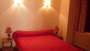 A room with a bed, two bedside lamps, and a wall-mounted light fixture.
