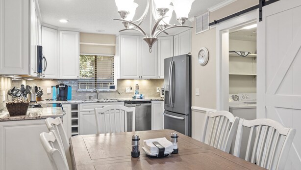 A modern kitchen with white cabinets, a wooden dining table, and a stainless steel refrigerator. - 28 Water Oak Villa | Special Fall Rates 2026 | Golf Views | Permit #077642 (Hilton Head Island)