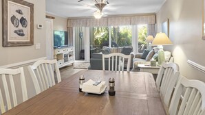 A dining area with a wooden table, white chairs, a chandelier, and a view of the outdoors. - 28 Water Oak Villa | Special Fall Rates 2026 | Golf Views | Permit #077642 (Hilton Head Island)