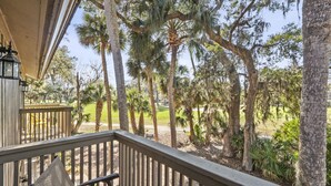 A balcony with a chair, overlooking a landscaped area with palm trees and a lawn. - 28 Water Oak Villa | Special Fall Rates 2026 | Golf Views | Permit #077642 (Hilton Head Island)