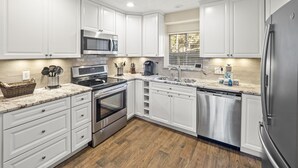 A modern kitchen with white cabinets, stainless steel appliances, and a wooden floor. - 28 Water Oak Villa | Special Fall Rates 2026 | Golf Views | Permit #077642 (Hilton Head Island)