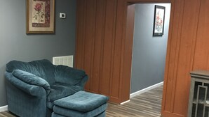 Une pièce avec un canapé bleu, des murs recouverts de panneaux de bois et un plancher en bois.
