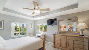 A bedroom with a bed, a dresser, a television, and a ceiling fan. - Calling all boaters and fishermen!  Canal front home with 10k lb boat lift! (North Fort Myers)