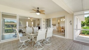 A spacious dining area with a white table and chairs, a ceiling fan, and large sliding glass doors leading to a patio. - Calling all boaters and fishermen!  Canal front home with 10k lb boat lift! (North Fort Myers)