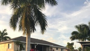 A house with a covered porch, a swimming pool, and palm trees. - Calling all boaters and fishermen!  Canal front home with 10k lb boat lift! (North Fort Myers)