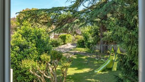 Ein Garten mit Rasenfläche, Schaukel und Rutsche.