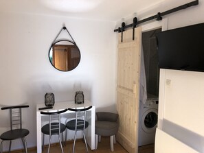 A compact kitchen with a washing machine, a dining table with chairs, a hanging mirror, and a sliding door. - Rental la baule in private residence near jumping and Benoît beach (Guerande)
