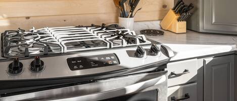 A stainless steel stove with four burners and a digital control panel.
