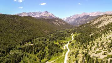 A mountainous landscape with a winding road, dense forests, and a clear sky.