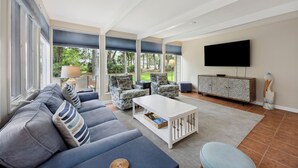 Un salón amplio con un sofá grande, dos sillones, una mesa de centro y un televisor fijado a la pared.