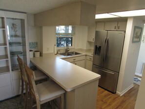 A compact kitchen with a stainless steel refrigerator, a sink, and a window.
