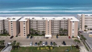 A multi-story hotel with a parking lot in front, a beach view, and a clear sky. - Beachside Sandcastle - Oceanfront, 1st-level Condo in Ponce Inlet (Ponce Inlet)