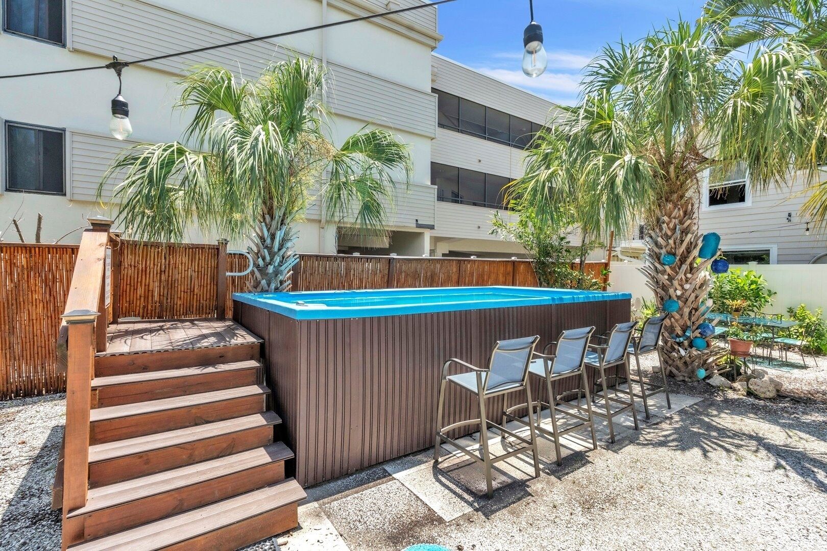 Un jardin avec une piscine, des marches en bois et un espace salon extérieur.