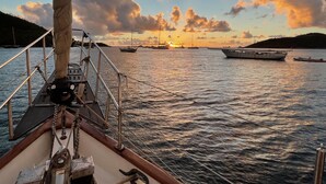 Um barco com vista para o mar e barcos ao longe durante o pôr do sol.