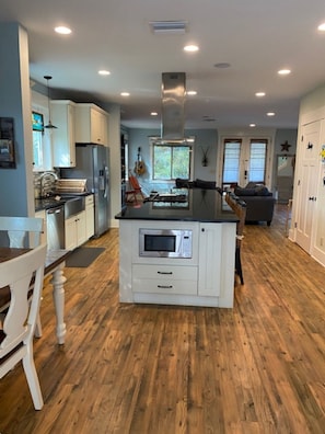 Modern kitchen with microwave and oven, stainless steel refrigerator, and wooden flooring.