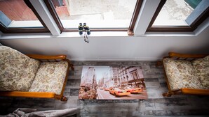 A room with two wooden chairs, a window with a view of the street, and a poster of a city street scene. - Stunning 5 Bed House in Campulung Moldovenesc (Campulung Moldovenesc)