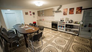A dining area with a round table and chairs, a kitchen with cabinets and appliances, and patterned floor tiles. - Stunning 5 Bed House in Campulung Moldovenesc (Campulung Moldovenesc)