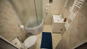 A bathroom with a toilet, a sink, a shower, and a blue rug. - Stunning 5 Bed House in Campulung Moldovenesc (Campulung Moldovenesc)