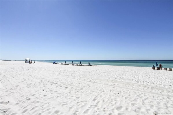 A wide sandy beach with a clear blue sky.